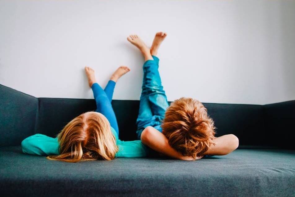 Enfants avec le confort de la climatisations, allongés jambes dressées contre le mur